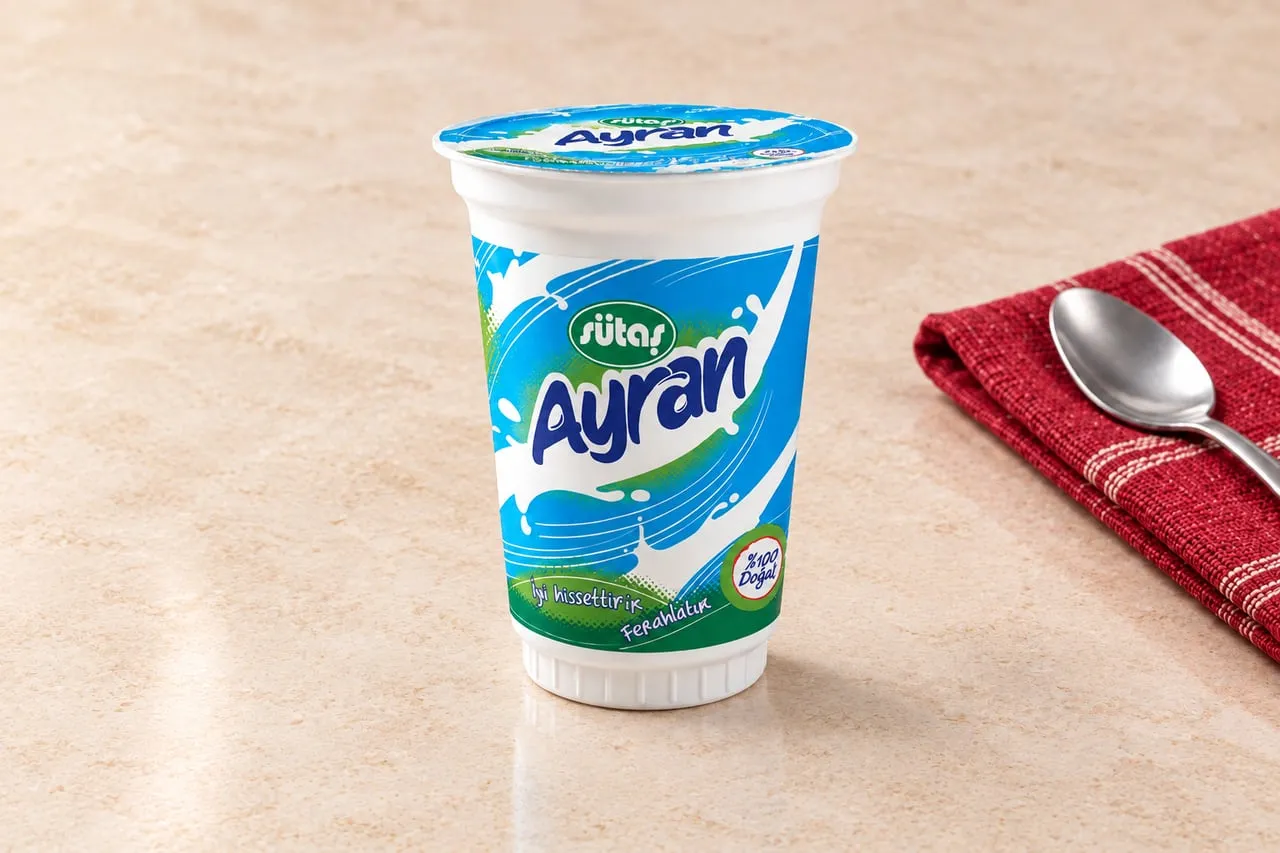 Mermer masada bardak ayran, yanında kırmızı peçete ve kaşık